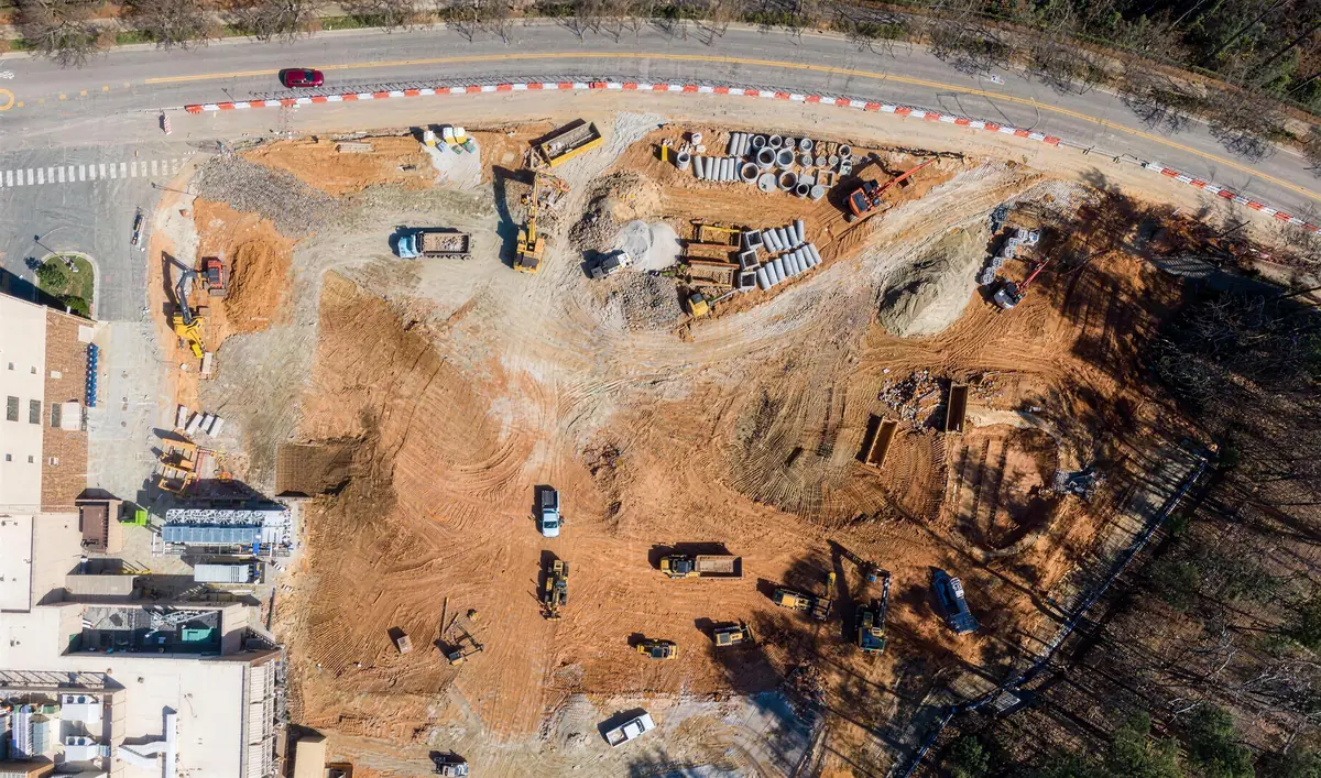 Aerial view of an active earthworks site with excavators and dozers cutting rock