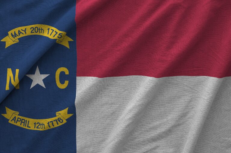 North carolina us state flag depicted on folded wavy fabric of old cloth